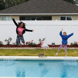 Two young girls, on of whom is deaf-blind, jumping into a pool.